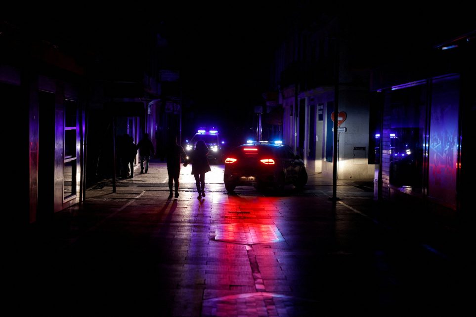 Photo: People walk along a shopping street without electric lighting as police cars patrol to prevent theft and looting in the stores during a power outage which hit large parts of Spain, in Ronda, Spain April 28, 2025. Credit: REUTERS/Jon Nazca