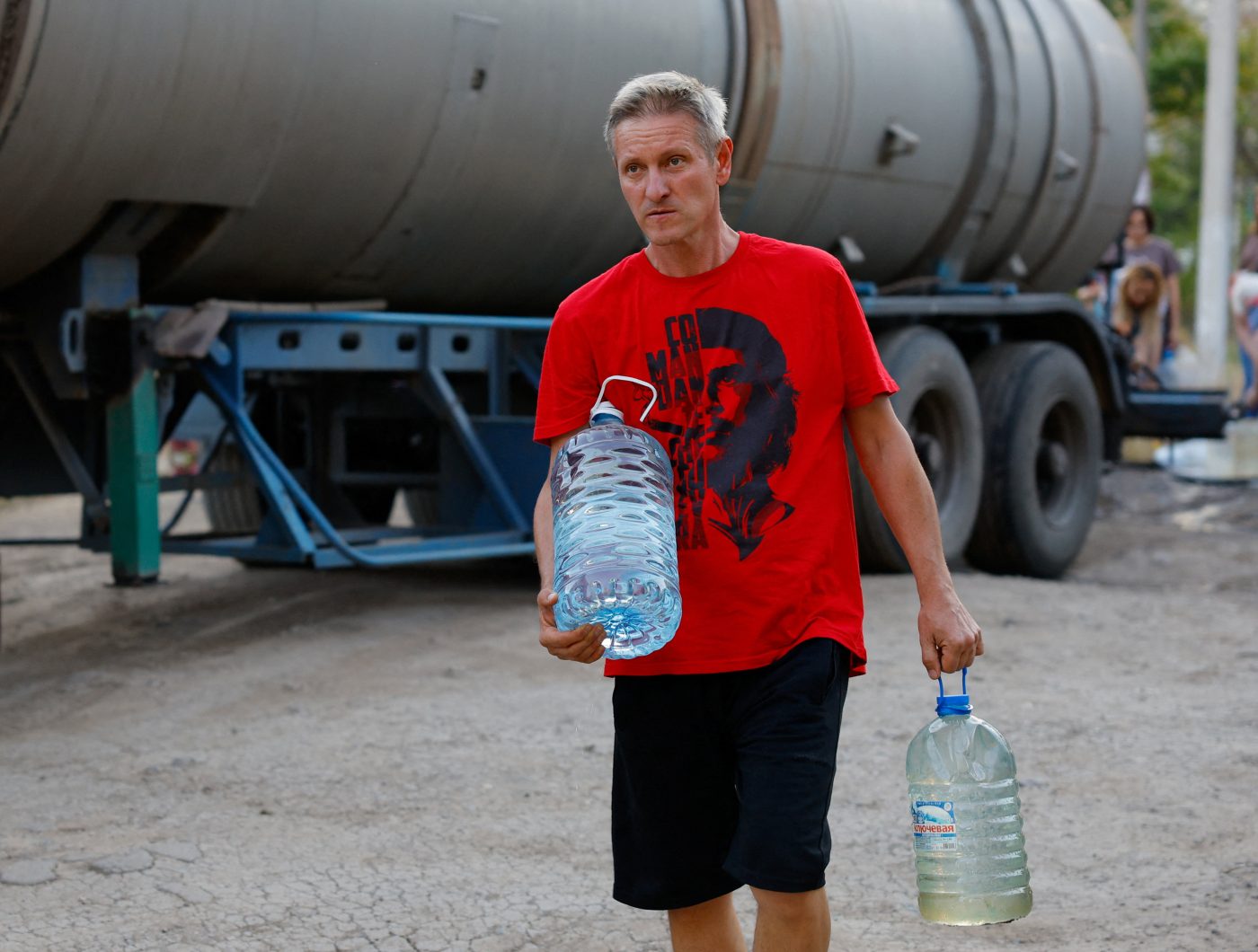 Photo: A local resident carries bottles of water collected from a tank truck in the course of Russia-Ukraine military conflict, in Donetsk, a Russian-controlled city of Ukraine, August 21, 2025. Credit: REUTERS/Alexander Ermochenko