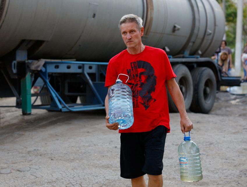 Photo: A local resident carries bottles of water collected from a tank truck in the course of Russia-Ukraine military conflict, in Donetsk, a Russian-controlled city of Ukraine, August 21, 2025. Credit: REUTERS/Alexander Ermochenko