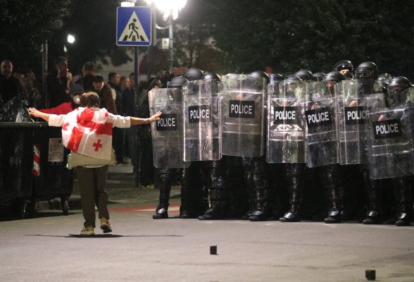 Photo: A protester wearing a Georgian flag walks towards police officers blocking the street during an opposition rally on the day of local elections in Tbilisi, Georgia October 4, 2025. Credit: REUTERS/Irakli Gedenidze
